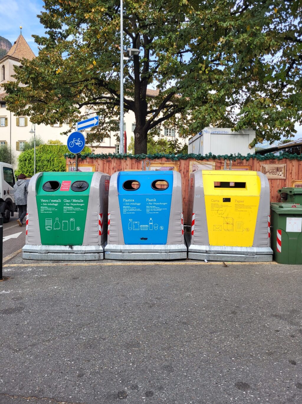 Drei SMART-Line Container, ein grüner für Glas, ein blauer für Plastik und ein gelber für Papier, stehen nebeneinander an einer Straßenecke. – Villiger Entsorgungssysteme AG