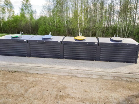 Vier Semi-Sub-Container stehen nebeneinander in einer ländlichen Gegend