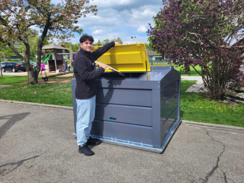 Person wirft Karton in Sub-Maxi-Container